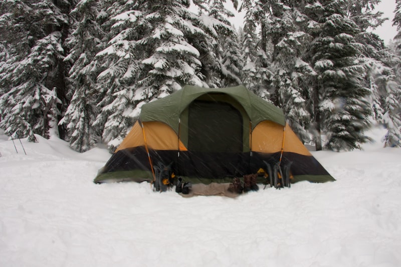 A small tent pitched on flat ground beside a calm lake in the evening.