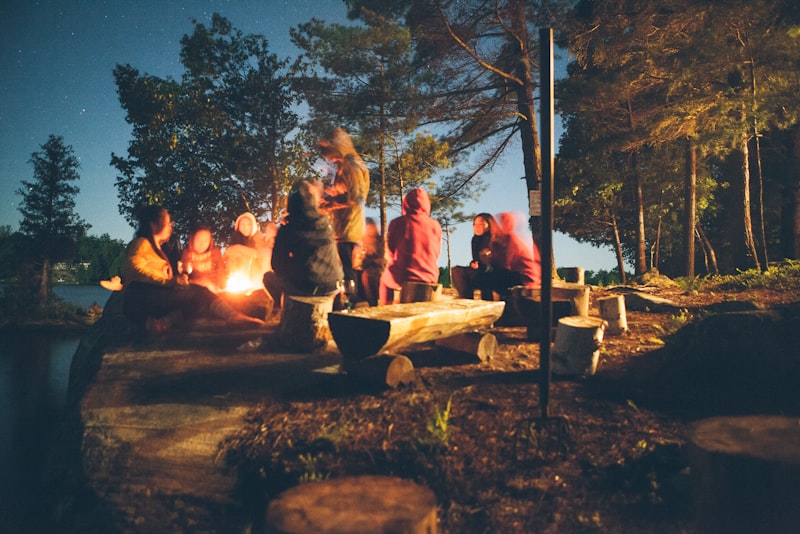 A small controlled campfire burning inside a stone ring at a campsite at dusk.