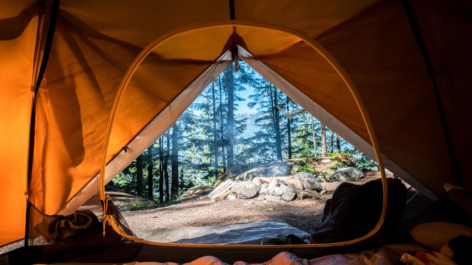 A lit tent glowing warmly at a campsite under a starry night sky.