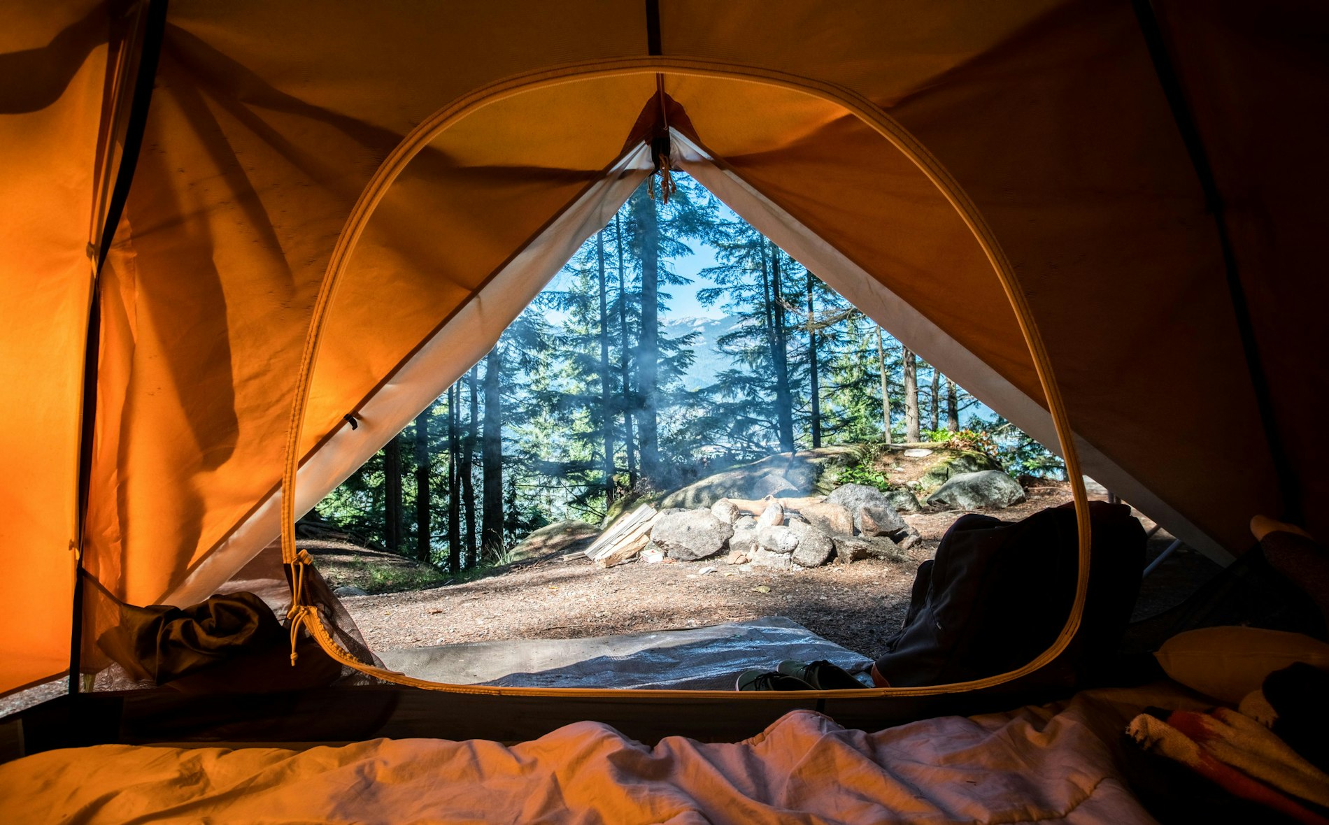 A lit tent glowing warmly at a campsite under a starry night sky.